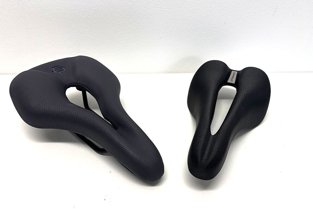 Sättel Zwei schwarze Fahrradsättel mit mittlerer Öffnung liegen nebeneinander auf einer weißen Fläche.