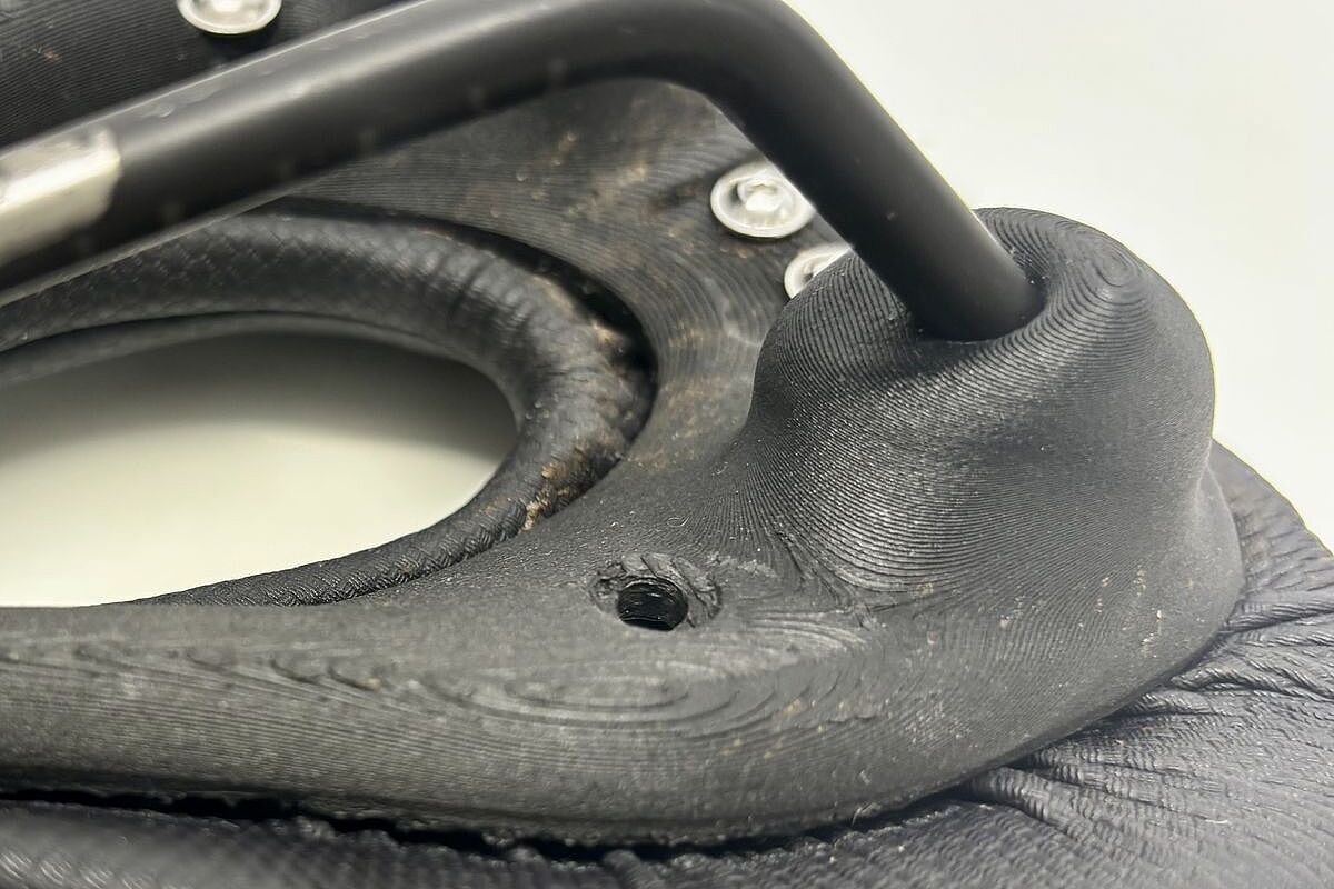 Fingerprint Detail Nahaufnahme eines schwarzen Fahrradsattels mit sichtbarer Befestigung und Schrauben auf der Unterseite.